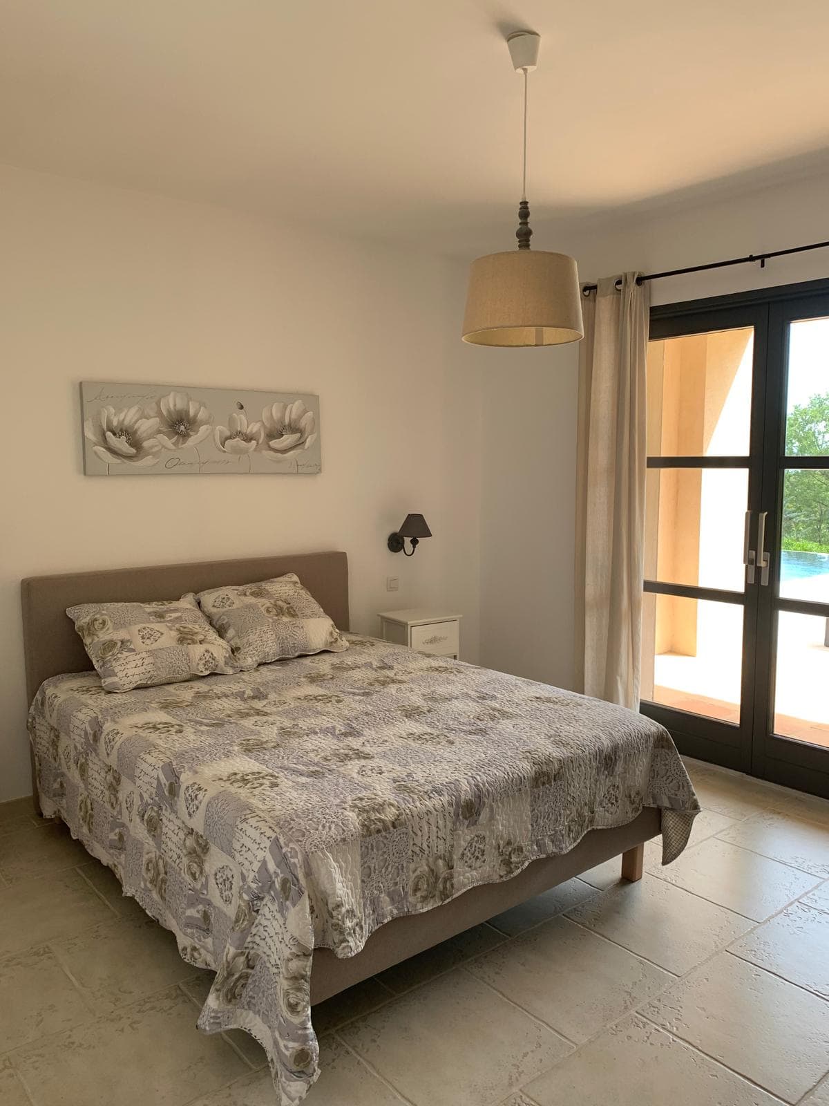 Drittes Schlafzimmer mit Doppelbett, Hängeleuchte und Glastüren zur Terrasse am Pool