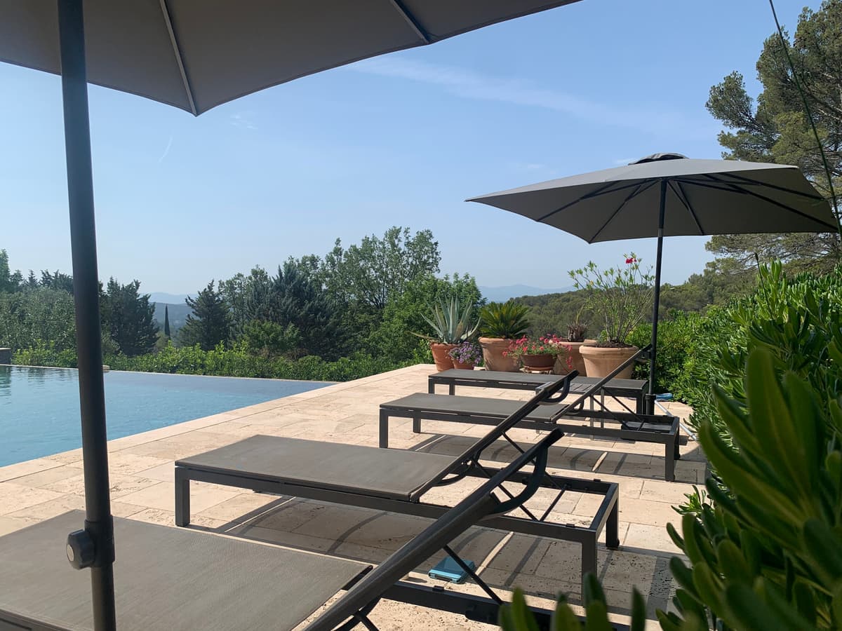 Pool mit Liegen und Sonnenschirmen an der Villa Lorgues, mit Blick über die Hügel des Var
