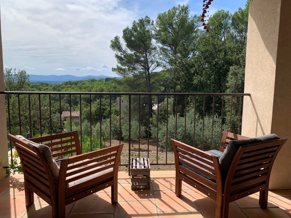 Terrasse mit Holzstühlen und Blick auf die Hügel